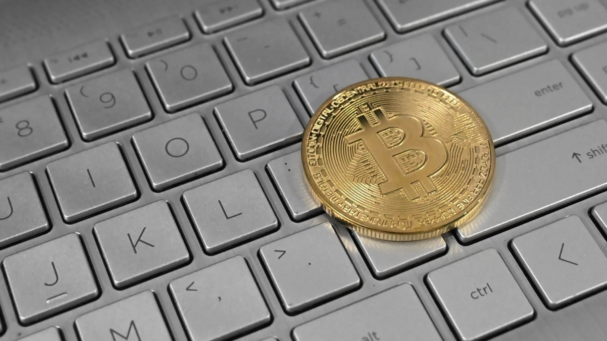 A gold-coloured Bitcoin coin on a laptop keyboard