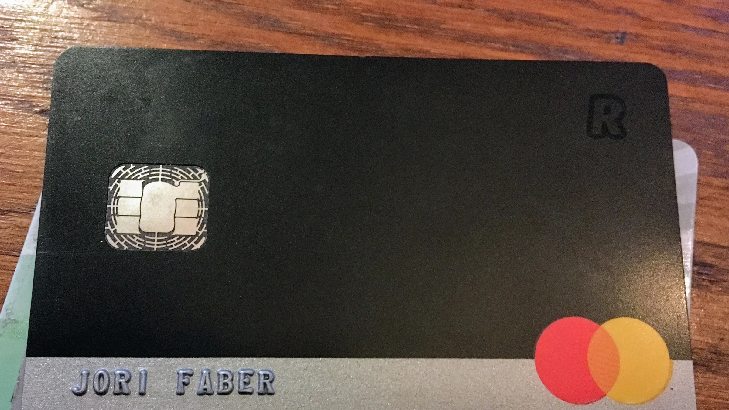 A black Revolut payment card resting on a wooden surface