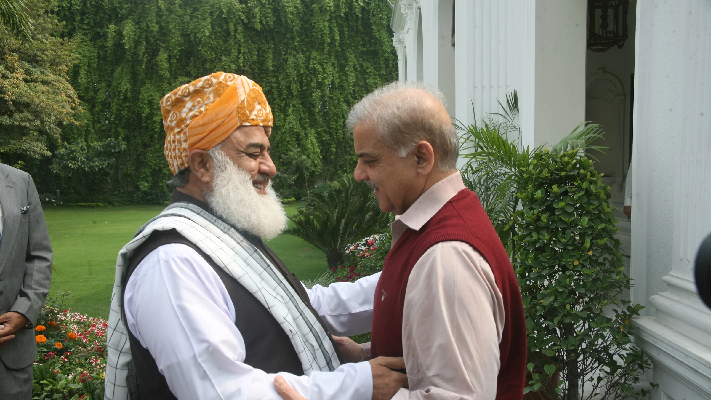 JUI-F chief Maulana Fazlur Rehman in a turban greets a guest in a garden