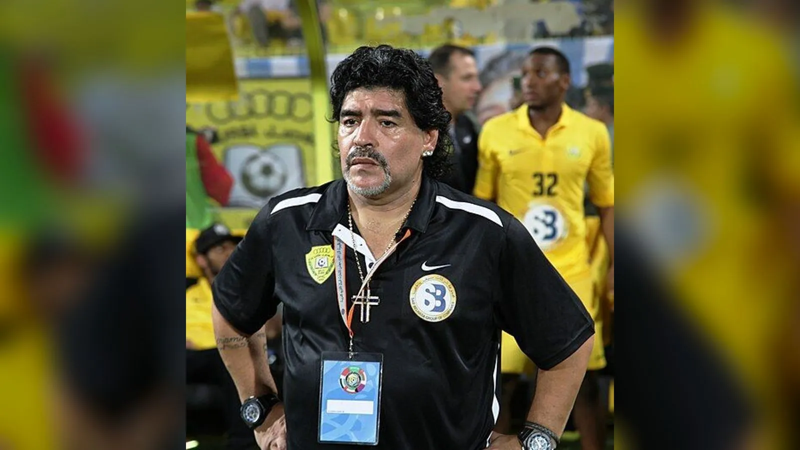 Diego Maradona standing on the touchline in a black coaching shirt