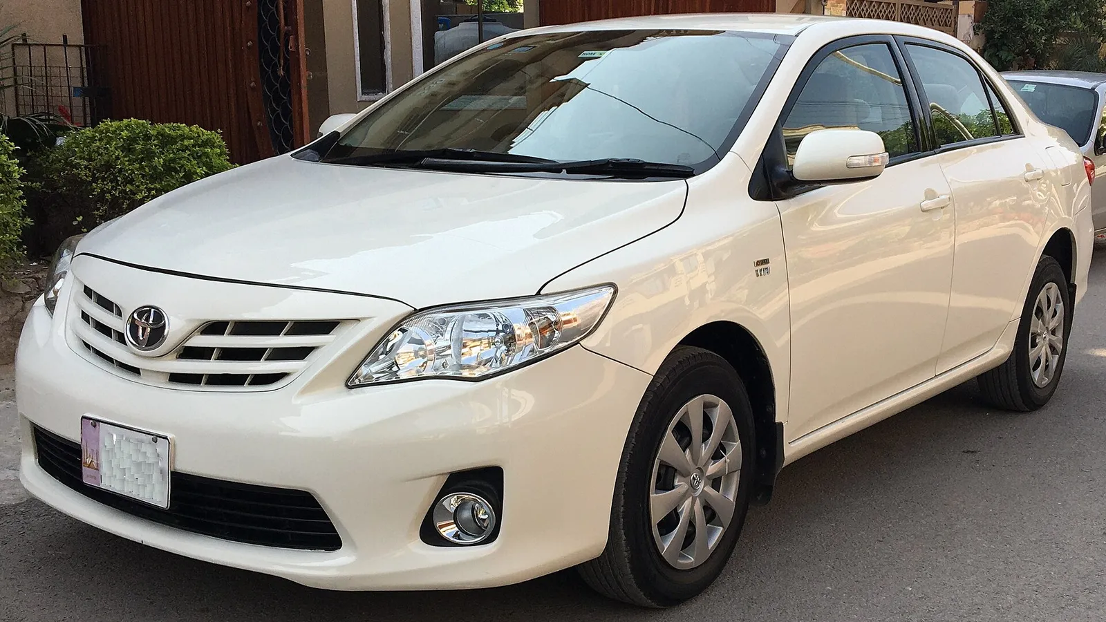 A white Toyota Corolla parked on a street in Pakistan