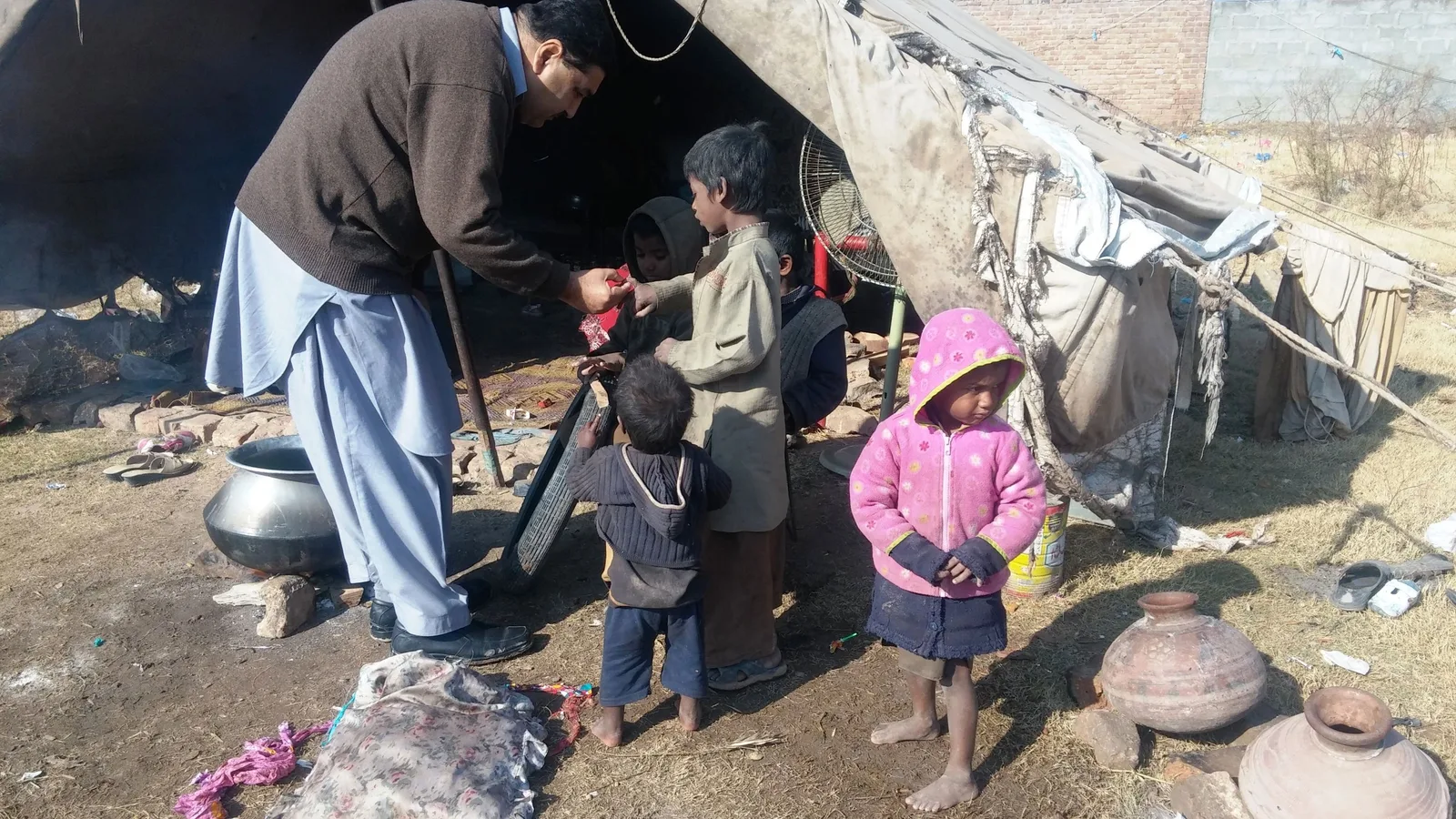 A health worker checking children near a tent during a polio vaccination campaign in rural Pakistan