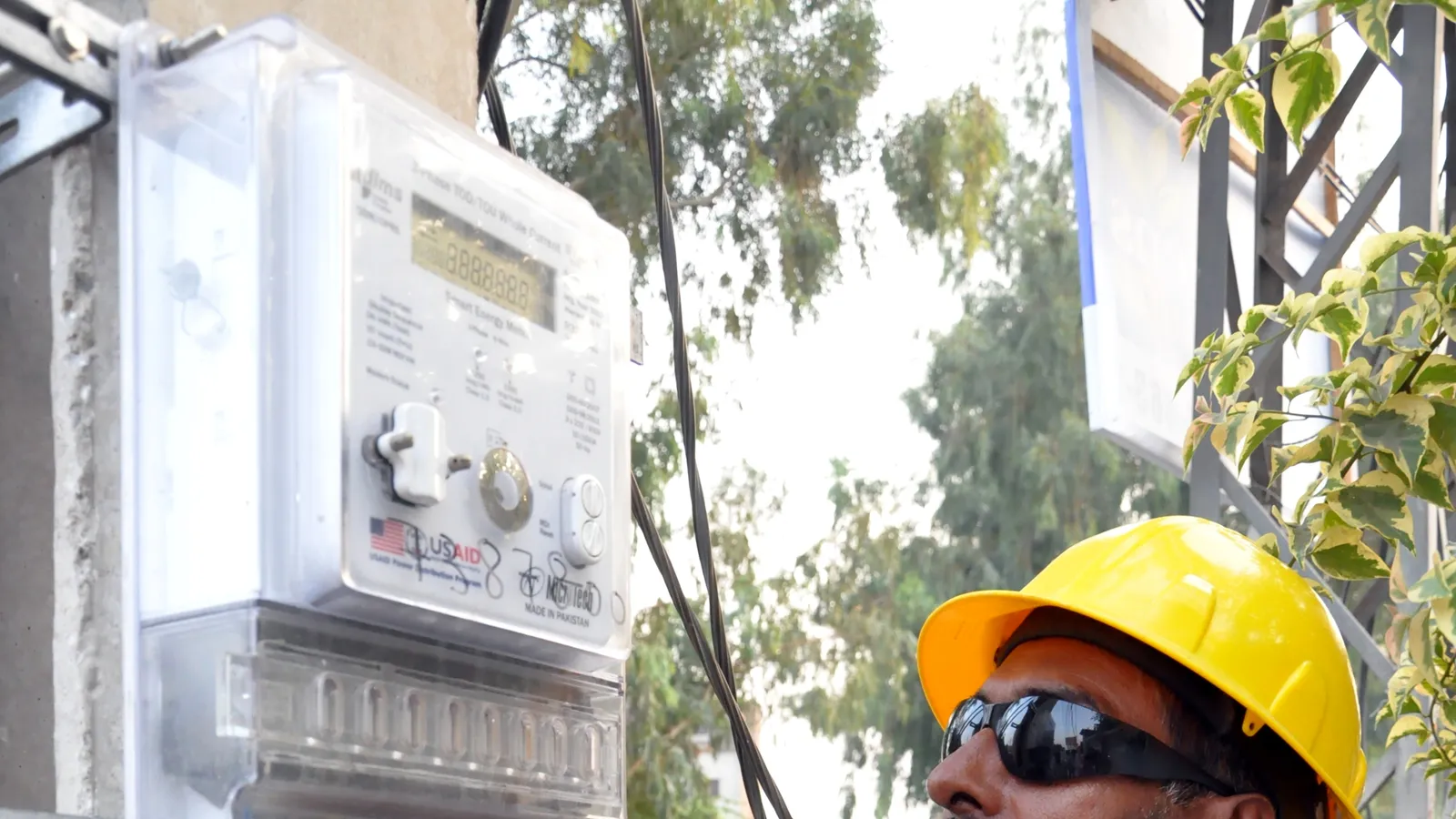 A technician next to an electricity meter installed at a home in Pakistan