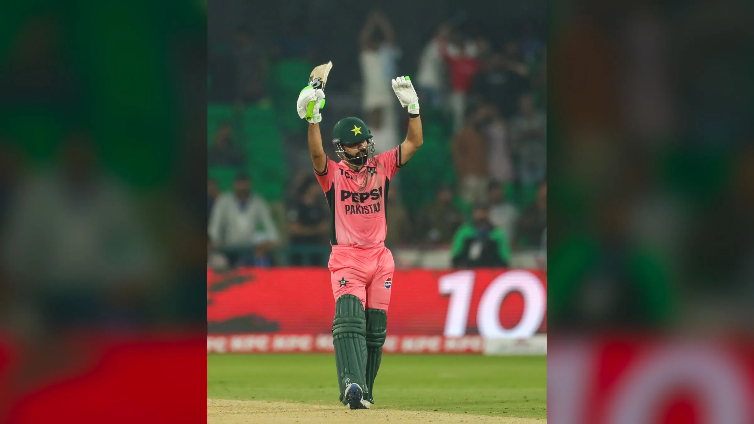 Shadab Khan raising his bat and gloves after reaching his century