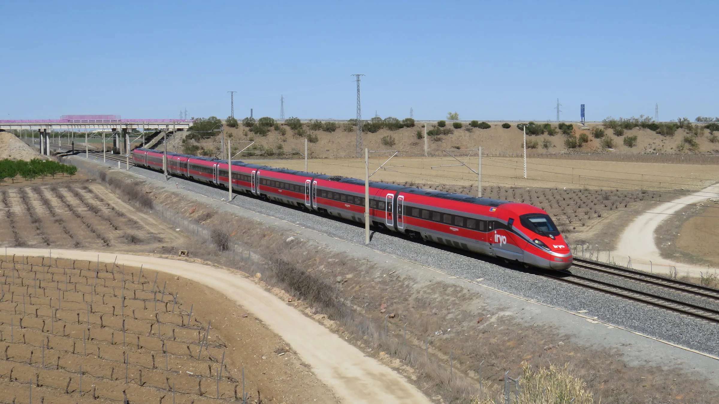 A red Iryo high-speed train running through the Spanish countryside