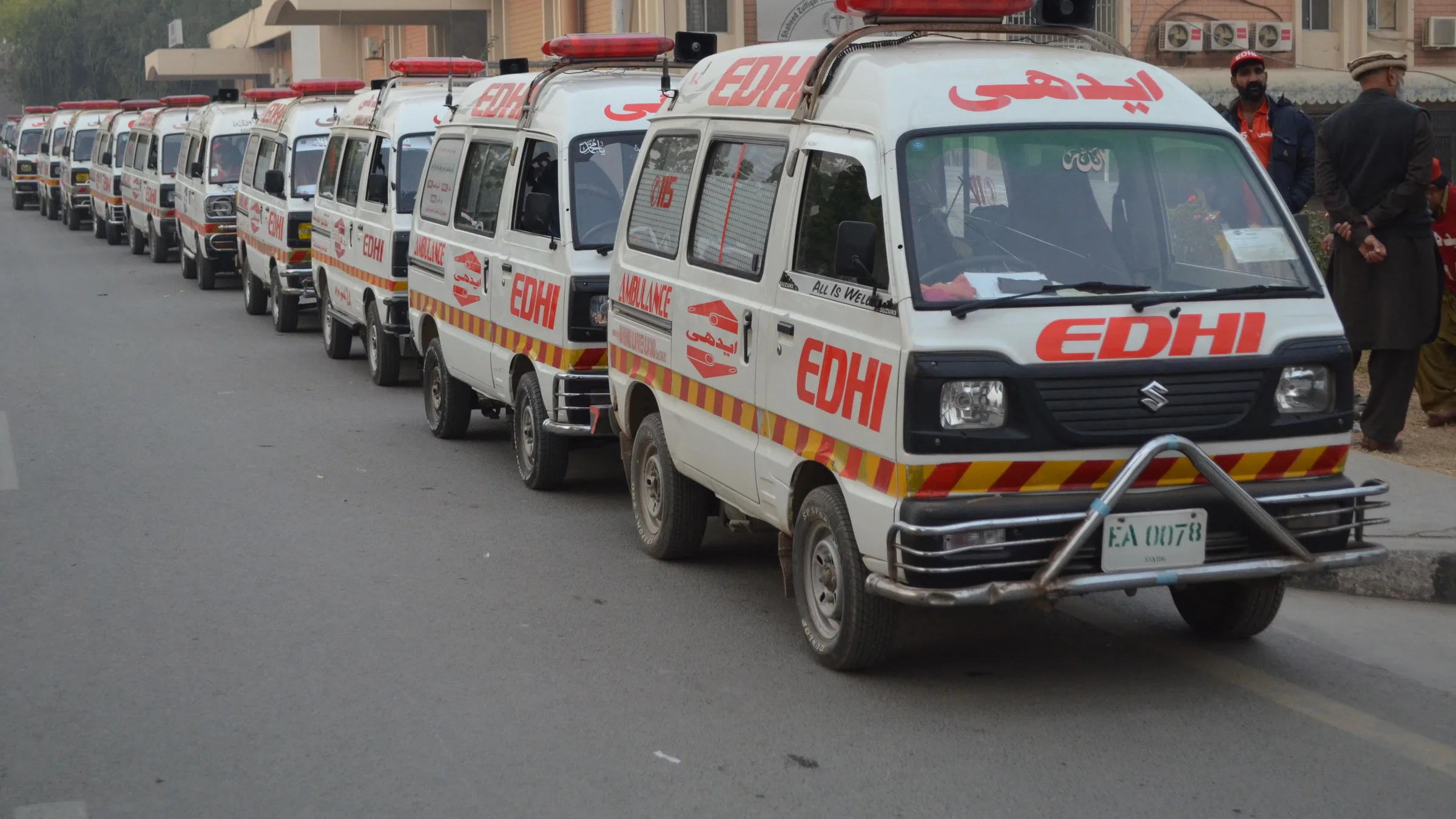 A line of Edhi Foundation ambulances parked along a road