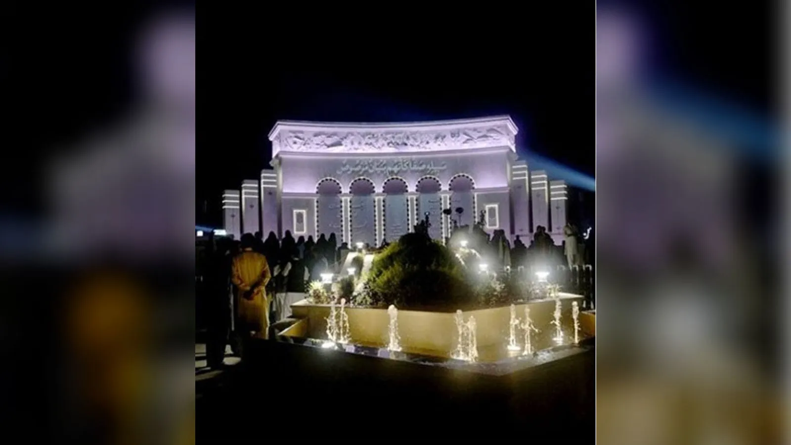 The illuminated Yadgar-e-Fatah monument in Islamabad at night with fountains in front